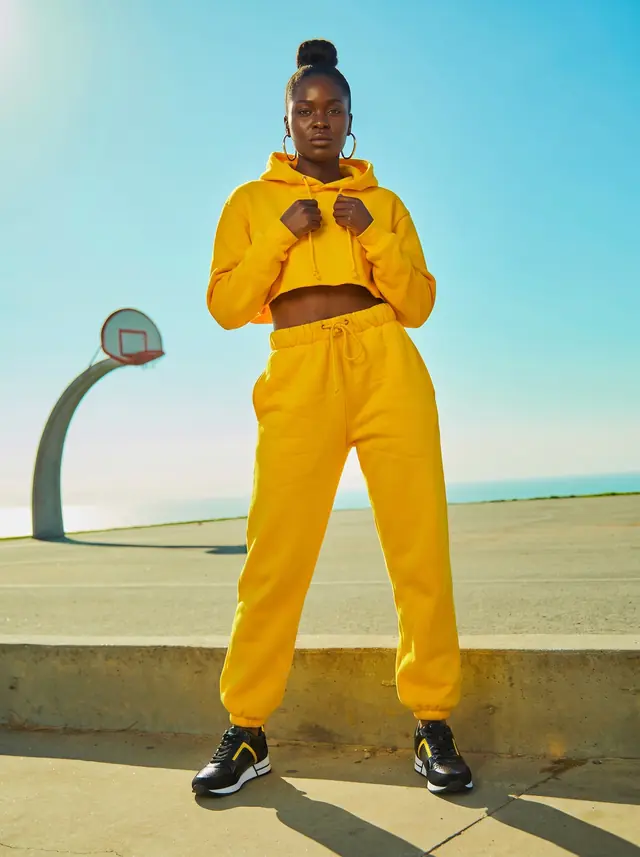 Une jeune femme en survetement jaune, sur un terrain de basket.